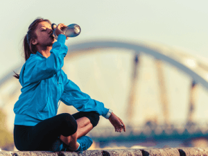 Jogger drinking water with bridge in background