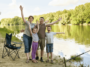 Smiling family posing for photograph by a river