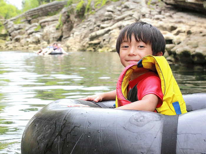 Child in an inflatable on a river smiling at camera