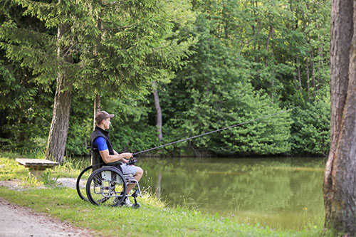 Disabled man on wheelchair fishing near a body of water