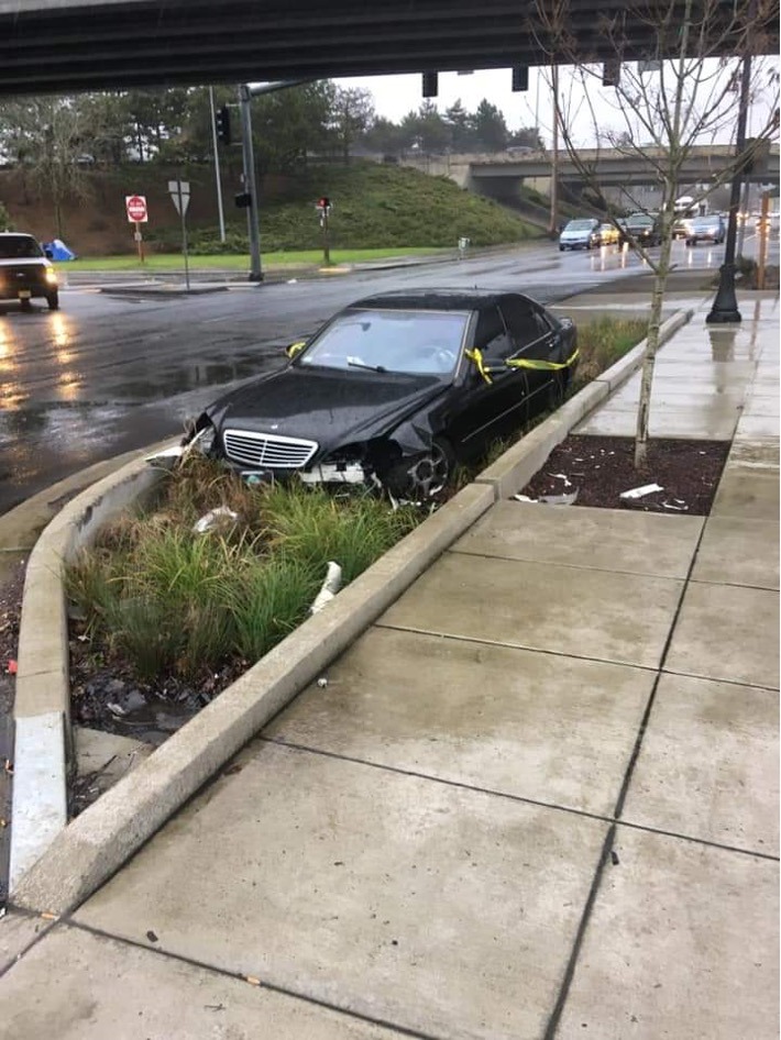 A black sedan in a street planter.